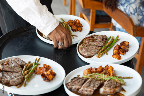 Canvastavla Waiter serving gourmet steak dinners with asparagus and roasted potatoes