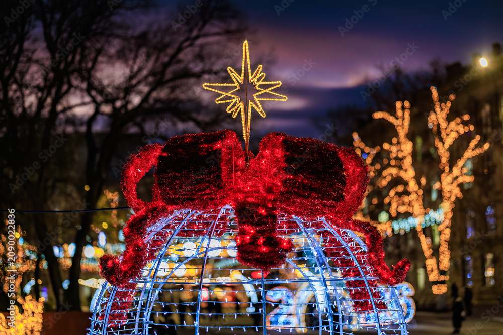 Obraz premium Festive illuminated christmas decoration with red bow and star in evening