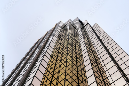 Modern glass skyscraper viewed from below against clear sky
