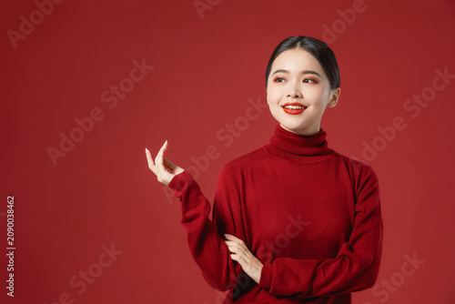 Konstfotografi Smiling young woman in red turtleneck gesturing on red background