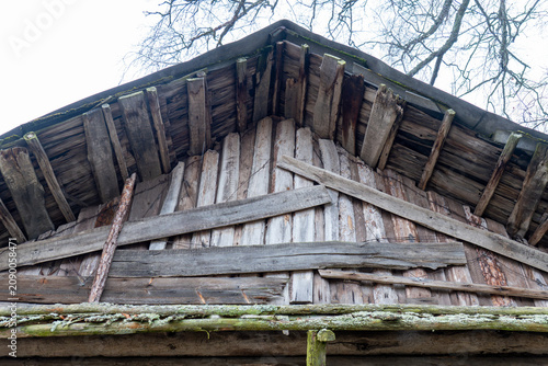 Bild auf Leinwand gable end of old abandoned wooden barn with weathered grey planks haphazardly na