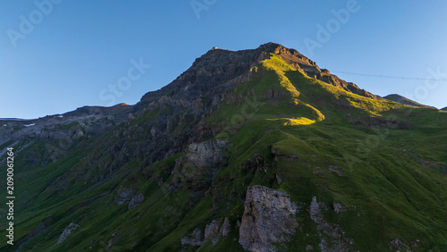 Canvas-taulu Golden hour light on steep green mountainside and rocky summit along the Walenpfad hiking route near Engelberg, Swiss Alps