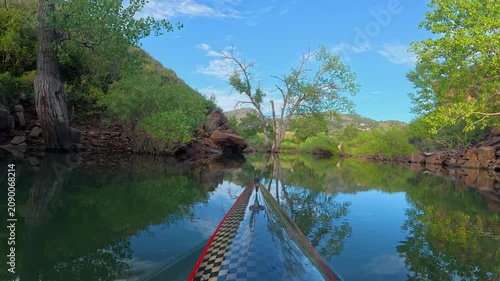 Relaxing POV kayaking through the scenic sandstone canyons of Horsetooth Reservoir in Fort Collins, Colorado. Peaceful summer morning paddle on calm water with the bow of a carbon fiber kayak.