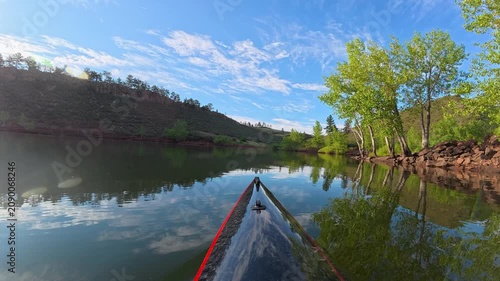 Relaxing POV kayaking through the scenic sandstone canyons of Horsetooth Reservoir in Fort Collins, Colorado. Peaceful summer morning paddle on calm water with the bow of a carbon fiber kayak.