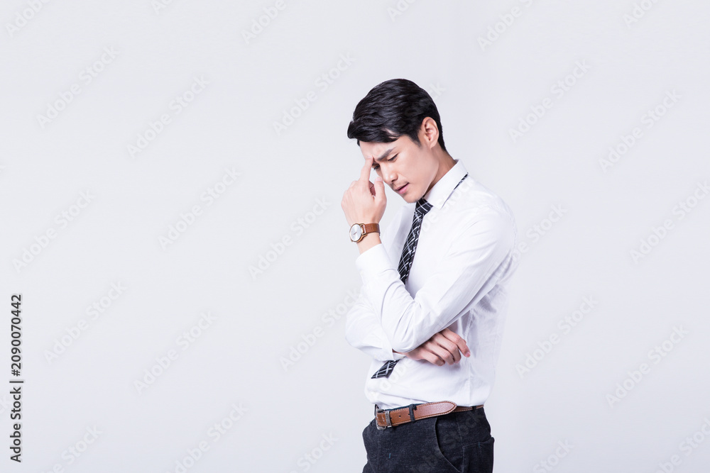 Naklejka premium Stressed young businessman with headache and worry on plain background