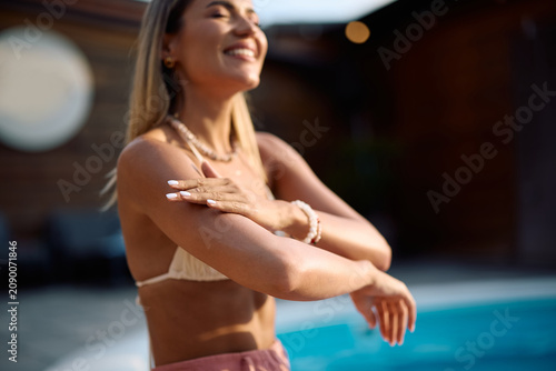Close up of woman protecting her skin during summer day at pool.