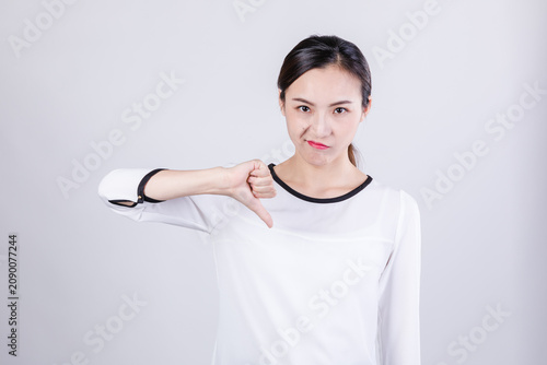 Foto Young woman showing thumbs down with displeased expression in studio