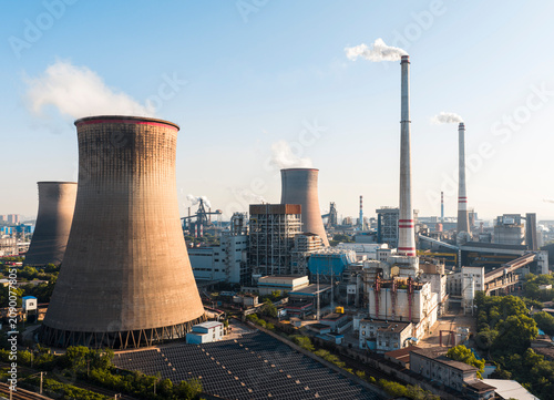 Wuhan Thermal Power Plant featuring gaint nuclear-style cooling towers and smokestacks, emitting heavy steam. It uses ultra-low emission, cogeneration for green energy transition. China.	