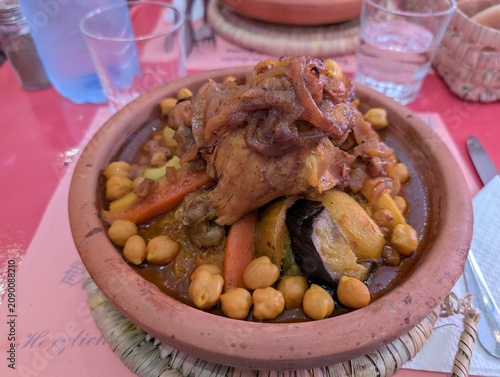 Fotografie Lamb tagine with chickpeas and roasted vegetables in a clay pot, Marrakesh, Morocco, on a sunny summer afternoon