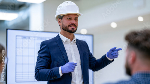 Quality Manager Presenting Corrective Action Plan on Monitor in Industrial Office