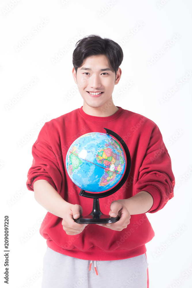 Fototapeta premium Smiling young man holding a world globe on white background
