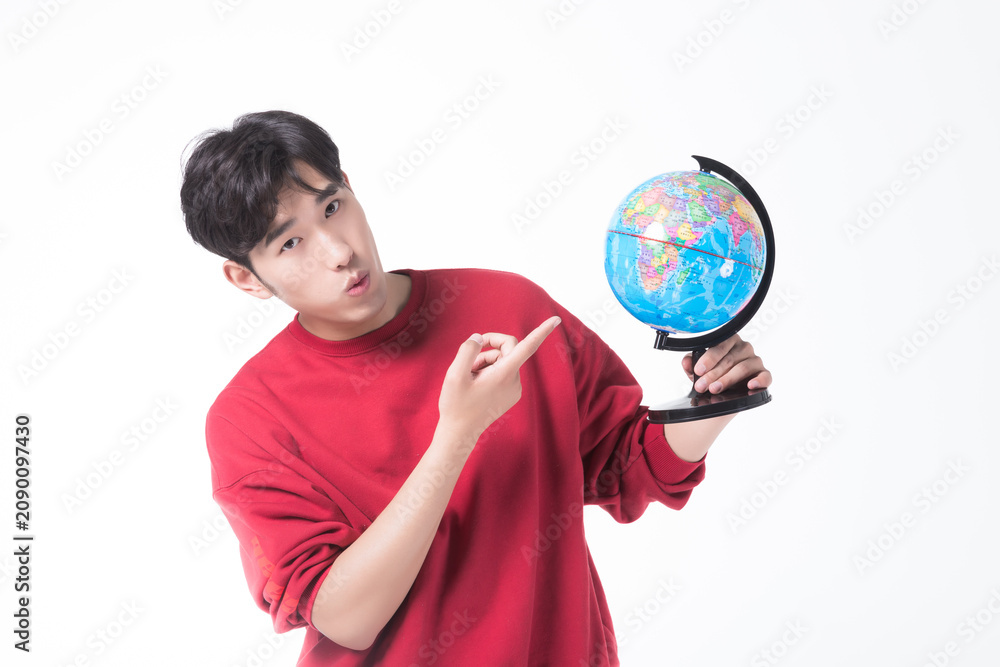 Fototapeta premium Young man pointing at globe on white background