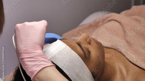 Extreme close up of microcurrent electrodes on African American woman's face. Professional lifting procedure for skin tightening and rejuvenation.
