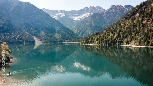 Obraz na płótnie Turquoise mountain lake reflecting alpine peaks, forested slopes, rocky shorelin