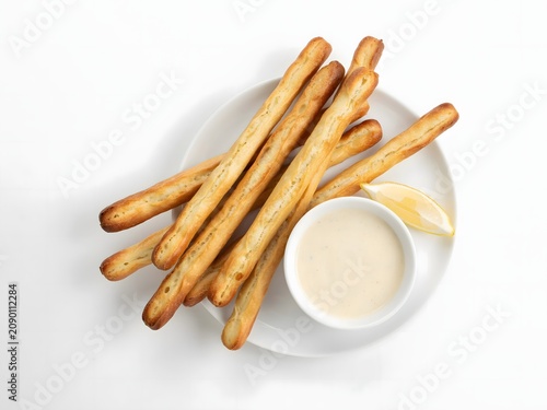 Breadsticks with dipping sauce and lemon wedge on plate