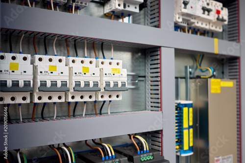 installed and wired electrical panel in industrial or commercial setting with neutral functional mood and side view of switches and terminal blocks on metal and plastic materials.