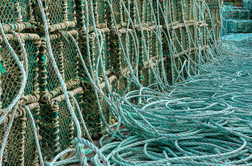 Quadro su tela Stack of green fishing traps with coiled ropes sitting on a wooden dock