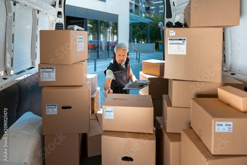 Foto A delivery worker is inside a delivery van surrounded by many cardboard boxes