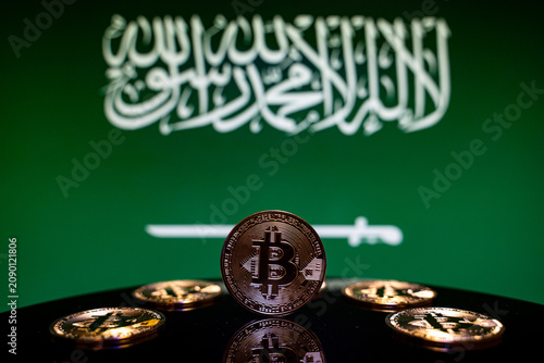 Close up of Bitcoin coins with Saudi Arabia flag background.