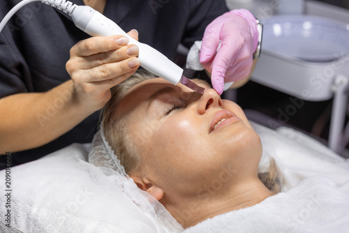 Canvastavla Professional cosmetologist uses an ultrasonic skin scrubber to gently exfoliate and cleanse facial skin, improving texture and promoting a smoother, healthier complexion