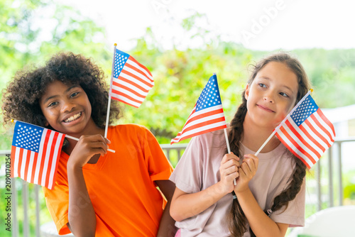 Fourth of July celebration with diverse children girl holding American flags for United States Independence Day expressing patriotism freedom national pride unity community spirit holiday happiness