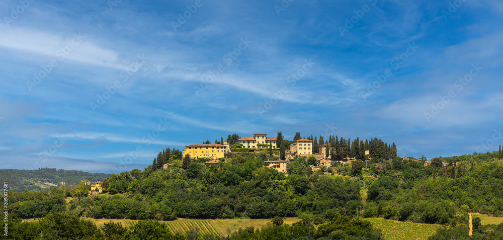 Obraz premium Scenic hilltop village in Tuscany, Italy. A Wide angle landscape shot of charming medieval italian village perched atop of rolling hill in the heart of the Tuscan countryside.