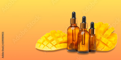 Canvas Print Bottles filled with mango oil rest beside sliced mango fruit