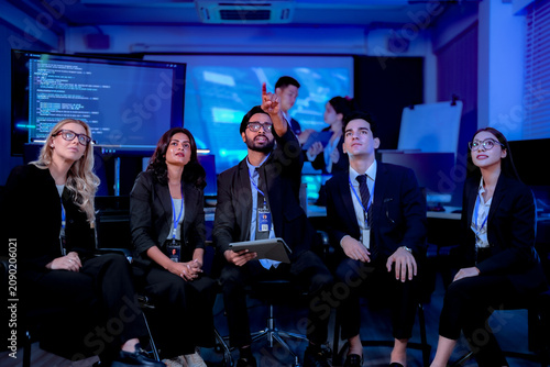 Delighted colleagues applauding and raising arms during a team win applauding the record quarter in a dark blue technology office at night captured in an authentic working moment.