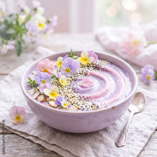 Healthy Purple Smoothie Bowl Topped with Edible Flowers and Seeds