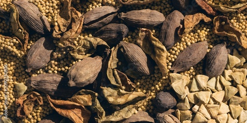 Overhead flat lay of Indian spice collection whole black cardamom dried curry leaves, mustard seeds, fenugreek