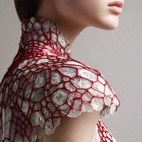Close up of woman wearing delicate white lace garment with red net overlay, showcasing intricate textile art and elegant design