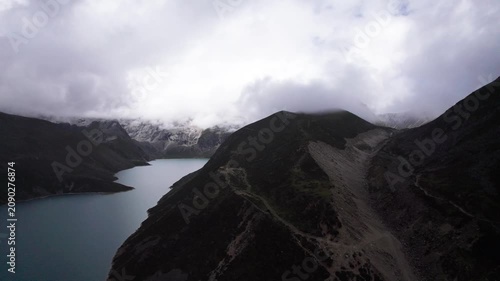 Drone view of Baimalincuo lake in Mount Kula Kangri in rainy day, well-built hiking trail circling its shore. 4k real time footage travel concept b roll shot.