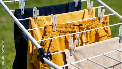 Close Up of Colorful Casual Clothes Hanging on Outdoor Drying Rack Under Bright Natural Sunlight During Laundry Day