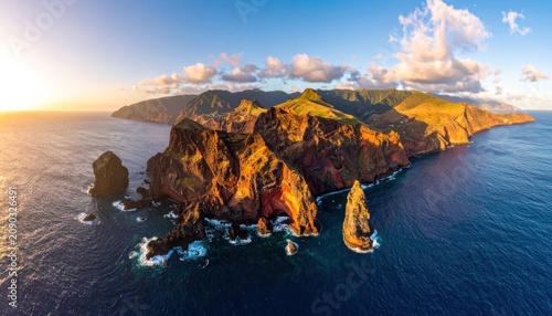Panoramic view of rugged, sun-drenched cliffs and sea stacks at sunset.