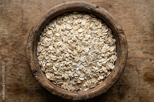 Organic Raw Rolled Oats in Rustic Wooden Bowl on Vintage Table Top Down View for Healthy Breakfast and Minimalist Food Design Flexible Layout Copy Space