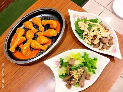 A delicious spread featuring spicy buffalo chicken drumsticks and two fresh healthy side salads