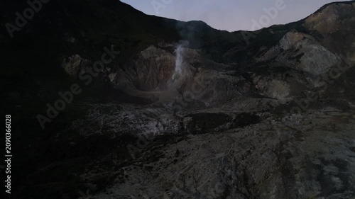 4k Drone video footage of the active crater of Mount Papandayan featuring rugged cliffs and sulfur-rich steam rising from volcanic vents in West Java, Indonesia.