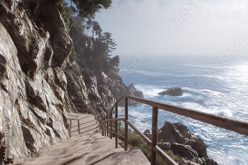 Concrete staircase descends along the rugged rocky cliffside overlooking the vast blue pacific ocean waves
