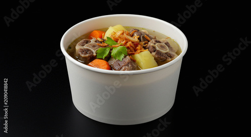Indonesian Oxtail Soup in White Paper Takeaway Bowl on Black