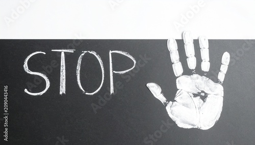 Stop word with chalk handprint on dark surface