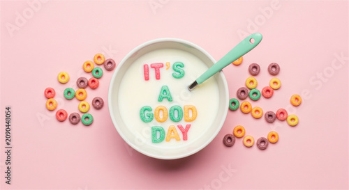 Positive quote cereal bowl with It's a Good Day text, colorful breakfast loops in milk, vibrant morning motivation on pink background