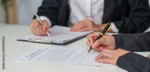 Cropped hands of business partners signing legal contract document in office