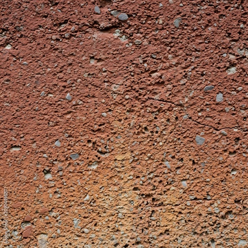 Rough Red Concrete Surface Showing Pebble Texture and Cracks in Close Up Detail