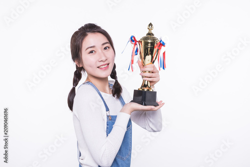 Smiling young woman holding trophy cup celebrating success