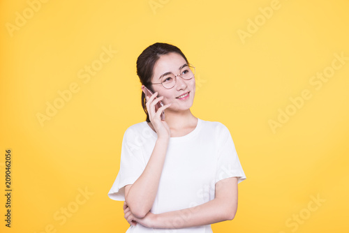 Smiling young woman talking on mobile phone on yellow background