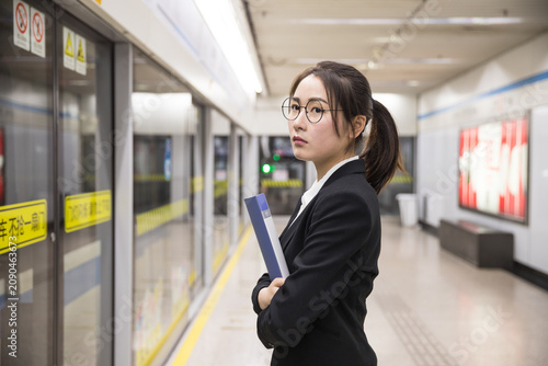 Young businesswoman waiting on subway platform after work