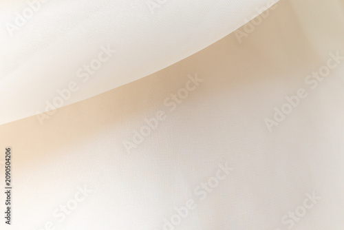 Soft delicate transparent organza, chiffon, silk fabric in cream, ivory, beige. Close up folds of fabric textile texture as background in champagne color with copy space.