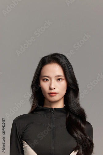 Young Asian Woman in Sleek Black Outfit on Gray Background