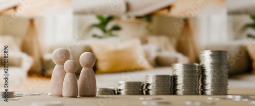 Tablou pe pânză Wooden family figurines standing beside a growing stack of silver coins on a tab