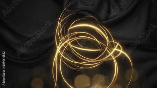 Golden light swirls over a dark and elegant fabric background
